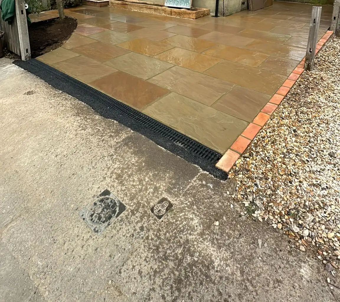 Camel Buff Indian sandstone driveway with a linear drain and red brick edge at a house in Surbiton