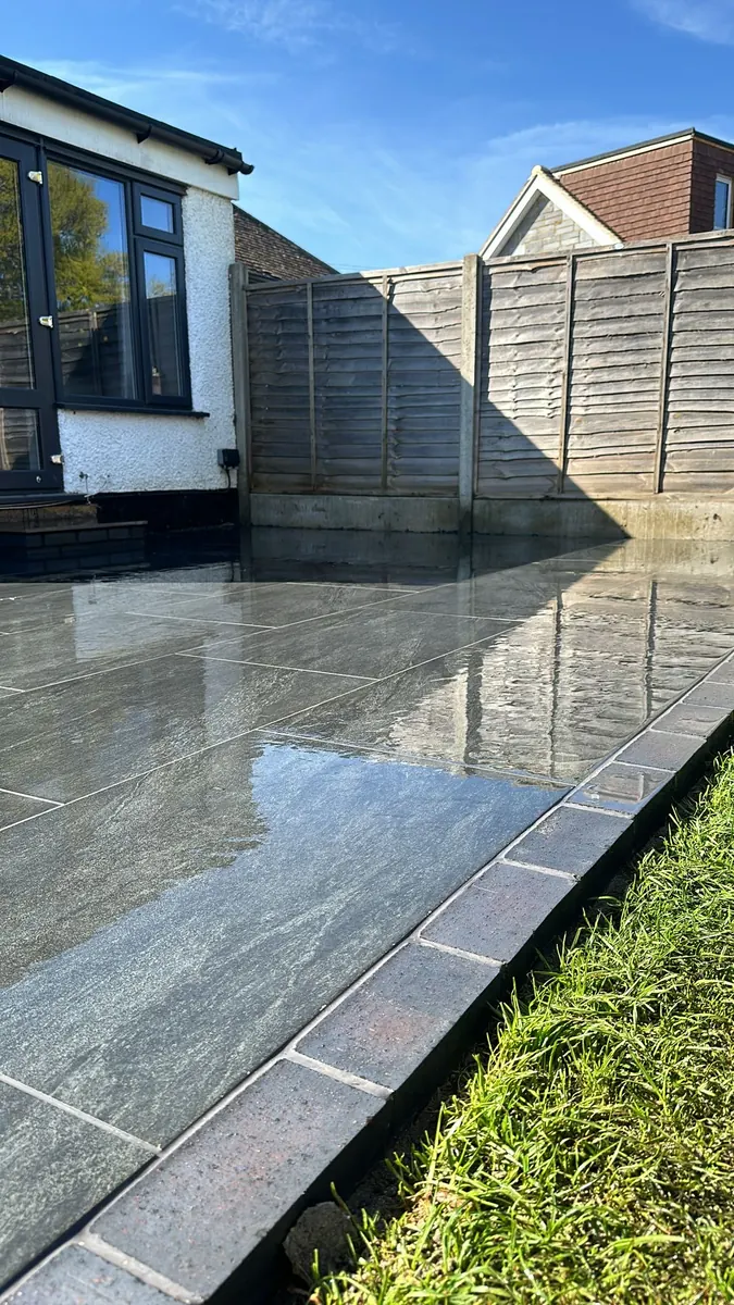 Dark brick picture frame edging between porcelain paving and the lawn, Addlestone