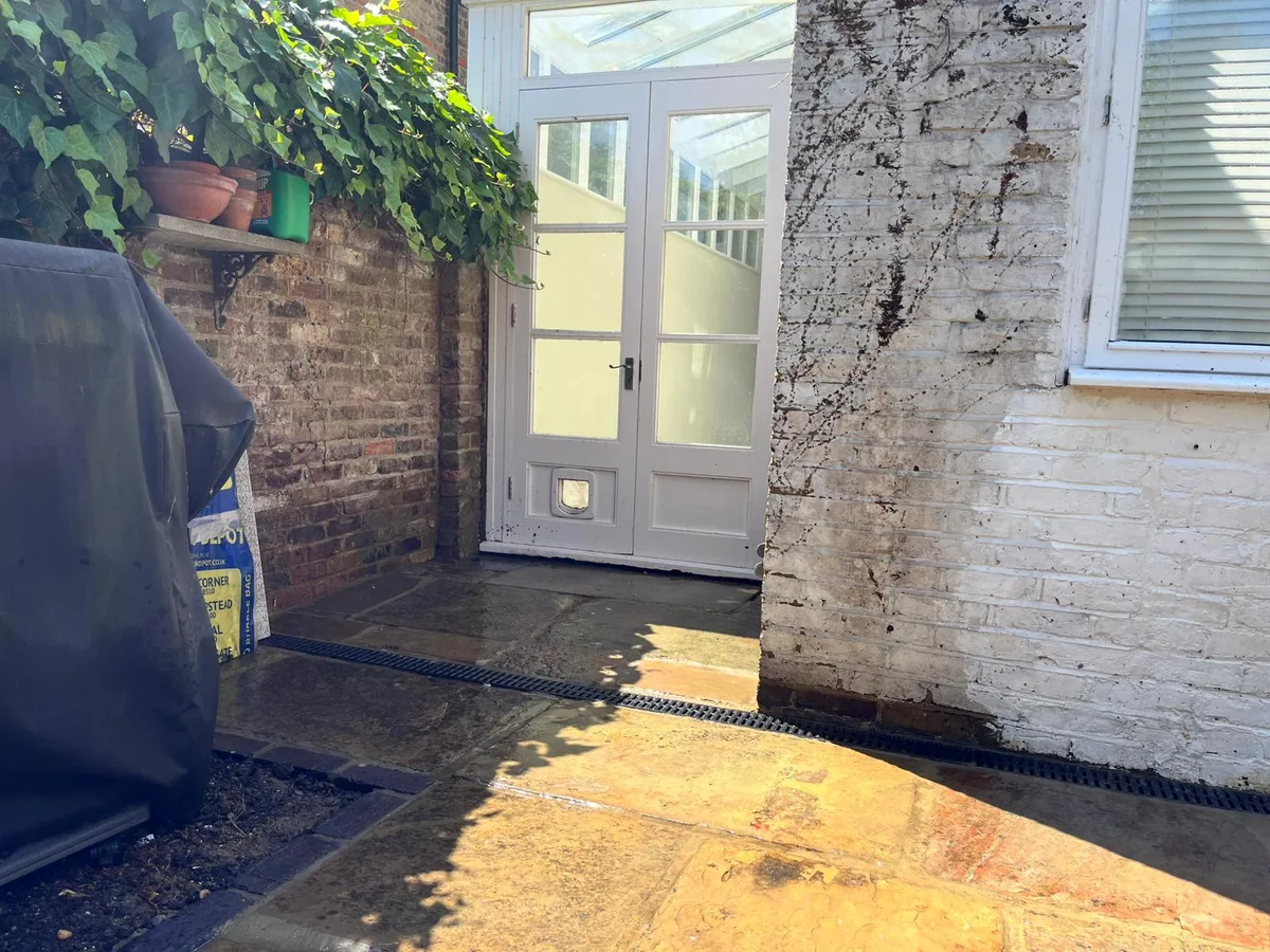 After: relaid stone patio with a new linear channel drain outside the back door, Kew