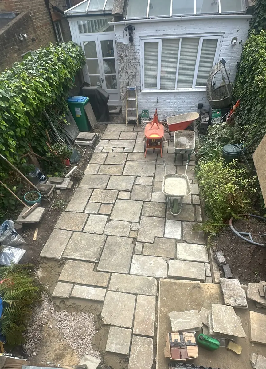 Before: the original stone patio being lifted in sections in a narrow Kew garden