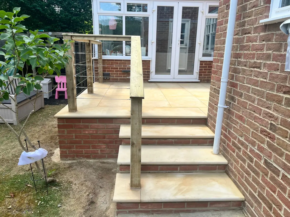 After: sandstone steps with bullnose treads leading up to the raised patio in Esher