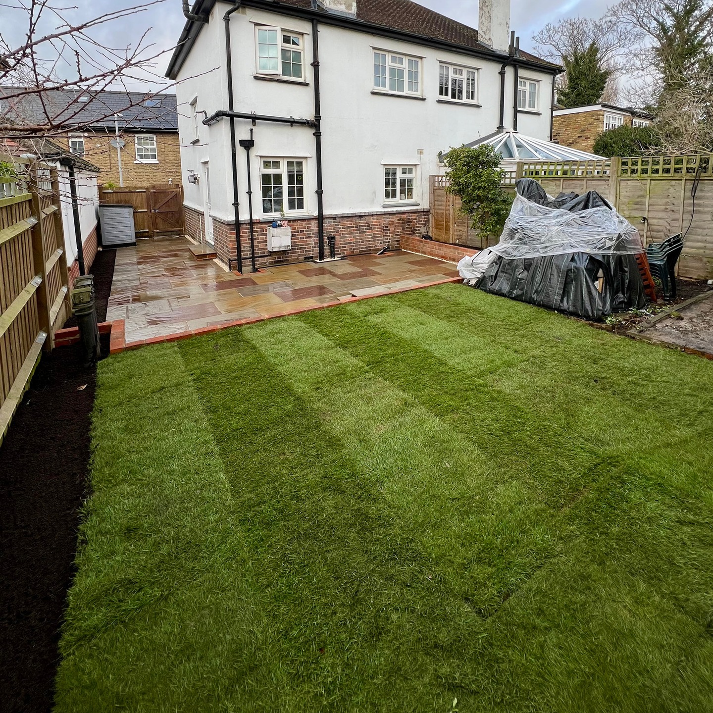 Clean Indian sandstone patio beside a new lawn in a Kingston garden