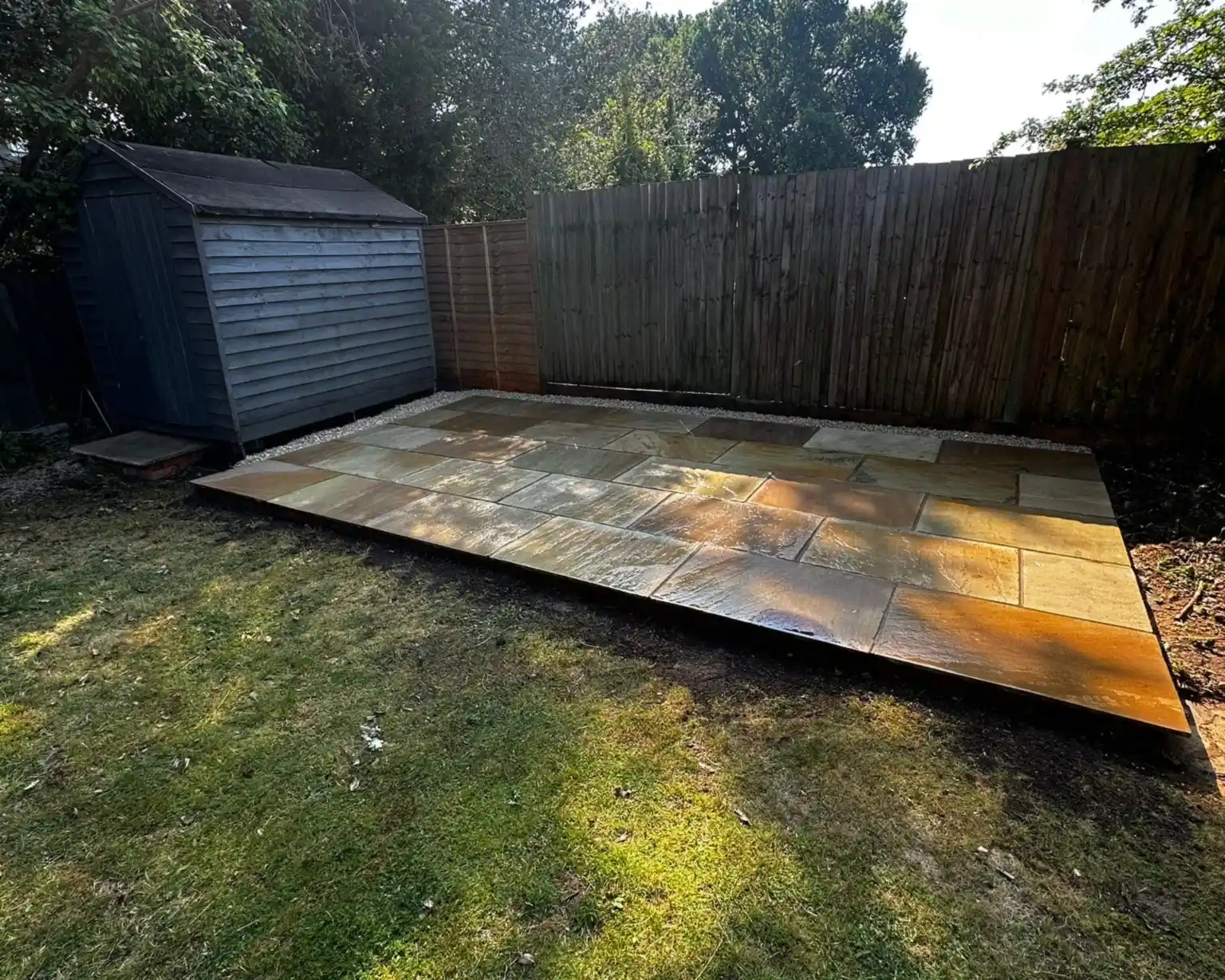 New mint sandstone patio in the corner of a garden in Claygate, next to a relocated shed