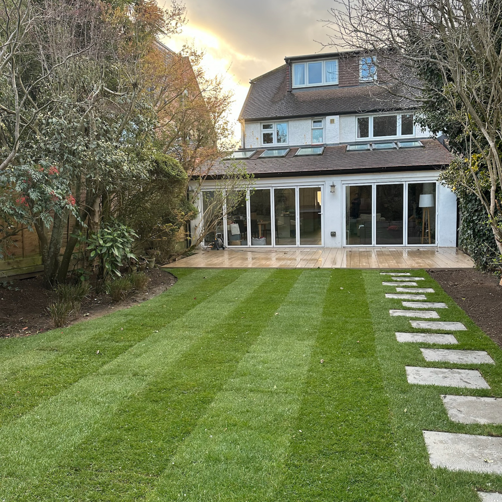 After: premium composite decking and a new striped lawn behind the same East Molesey house