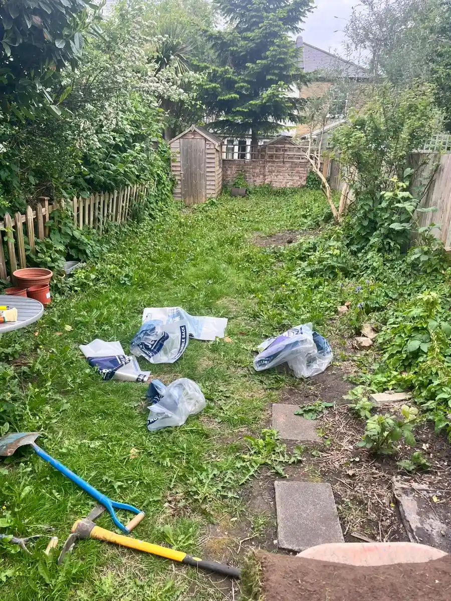 Before: overgrown back garden with weeds and broken slabs in Kingston