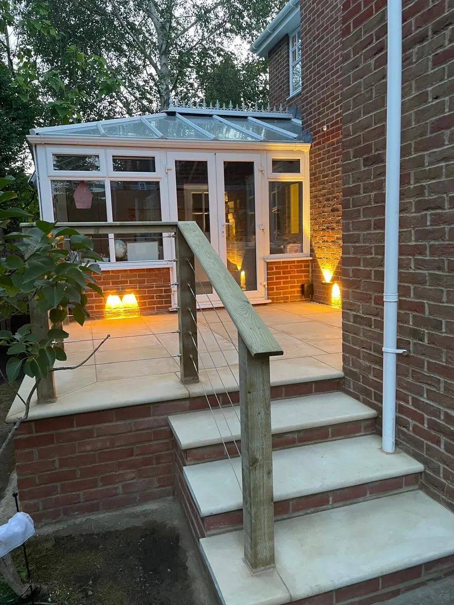 Raised sandstone patio and bullnose steps lit at dusk, Esher