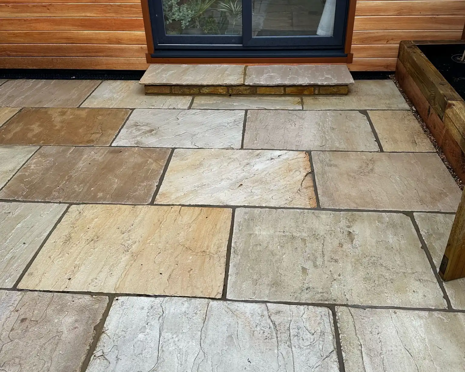 Fossil Mint Indian sandstone courtyard in front of a cedar clad garden room in Twickenham