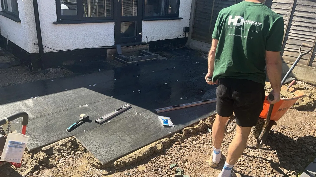Large format porcelain slabs being laid and levelled on a sand and cement bed in Addlestone