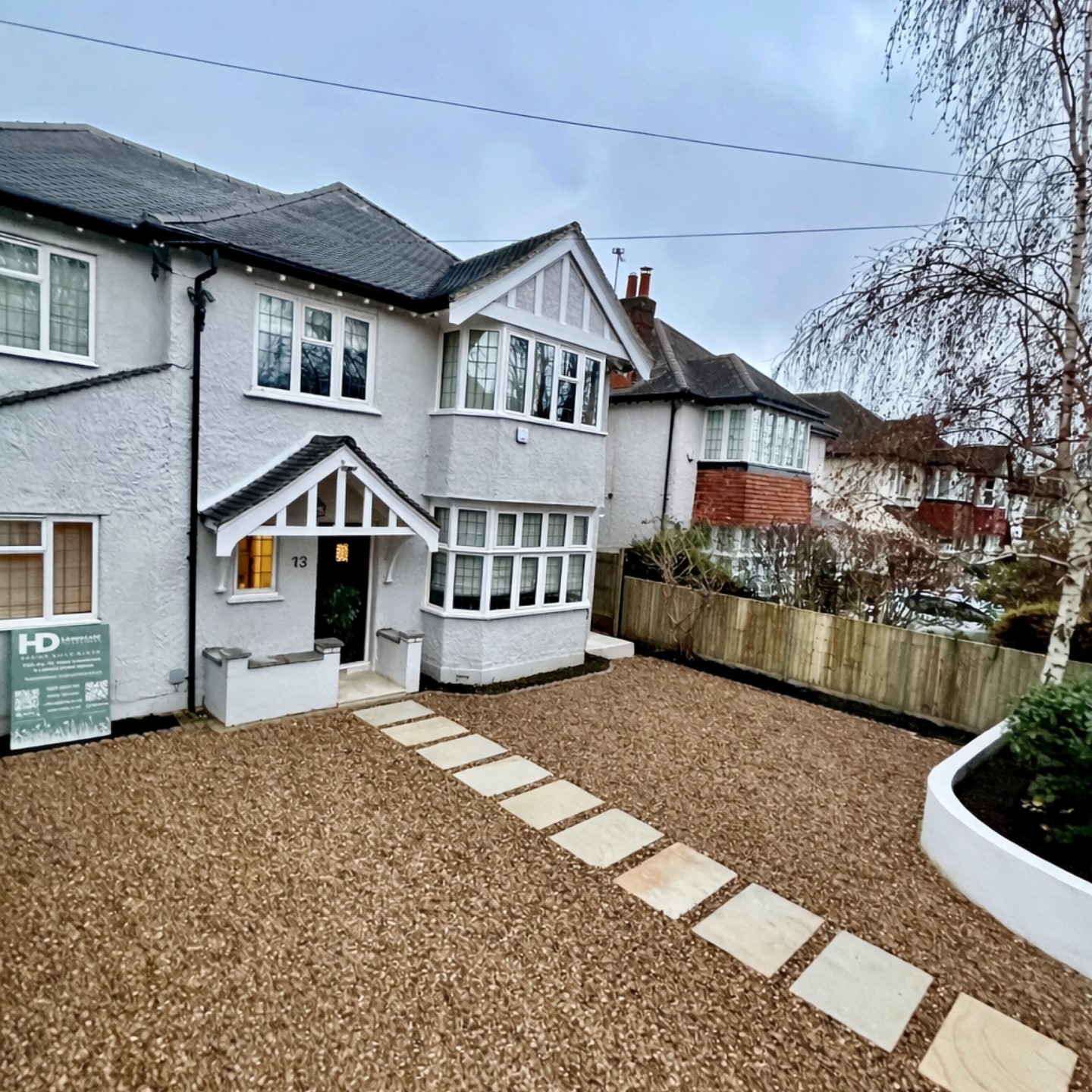 New gravel driveway, sandstone stepping path and curved rendered planter at the front of a 1930s house in East Molesey