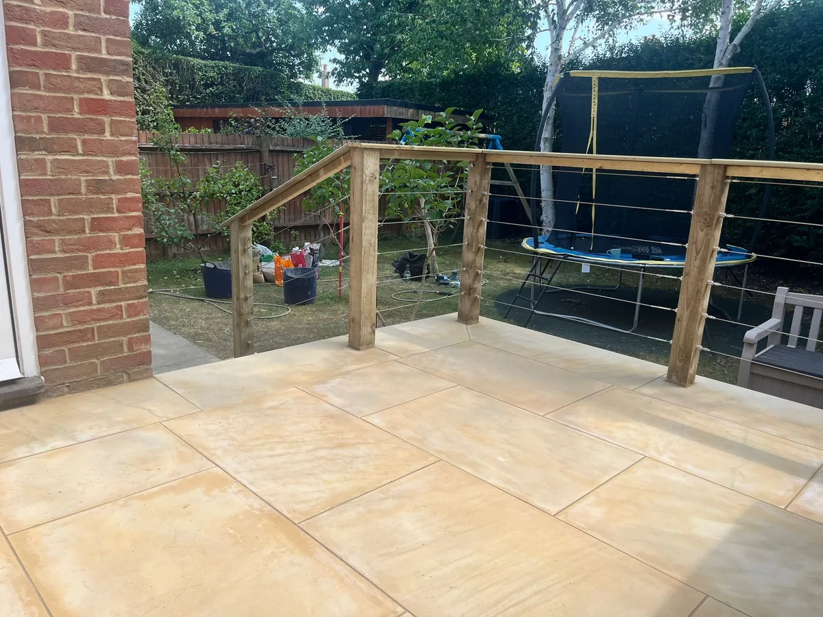 Sandstone terrace surface with timber posts and wire balustrade overlooking the garden, Esher