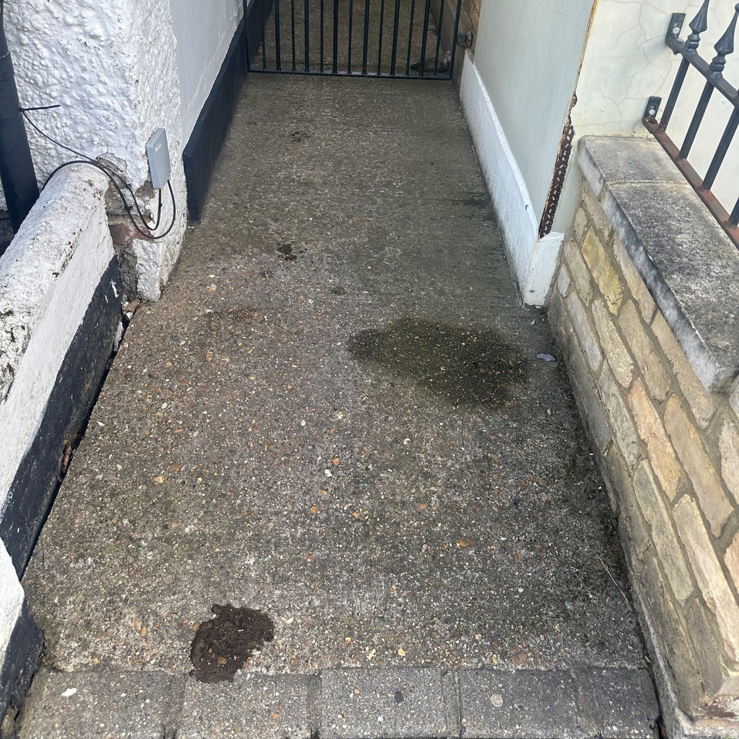Weathered concrete alleyway and failing front wall in Twickenham before the path and wall rebuild